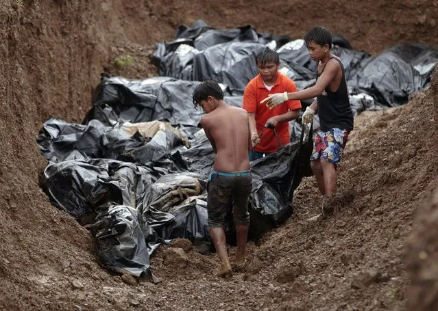 Filipino workers arrange body bags at a mass burial site at the Basper public cemetery in Tacloban, Leyte province, central Philippines on Thursday, November 14, 2013. Typhoon Haiyan, one of the most powerful storms on record, hit the country's eastern seaboard on Friday, destroying tens of thousands of buildings and displacing hundreds of thousands of people. (Photo by Aaron Favila/AP Photo)