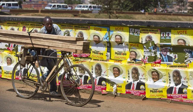 A man pushes his bicycle laden with wood past campaign posters for long-time President Yoweri Museveni, as well as for local members of Parliament, on a street in Kampala, Uganda Wednesday, February 17, 2016. (Photo by Ben Curtis/AP Photo)
