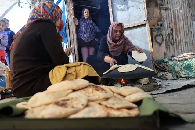 Women bake bread using a makeshift wood stove in Rafah in the southern Gaza Strip on November 25, 2023. Trucks carrying aid, including fuel, food and medicine, began moving into Gaza through the Rafah crossing from Egypt shortly after a truce began at 7:00 am (0500 GMT) on November 24, the biggest humanitarian convoy to enter the besieged territory since the war started on October 7 between Israel and the Palestinian Hamas movement. (Photo by Said Khatib/AFP Photo)