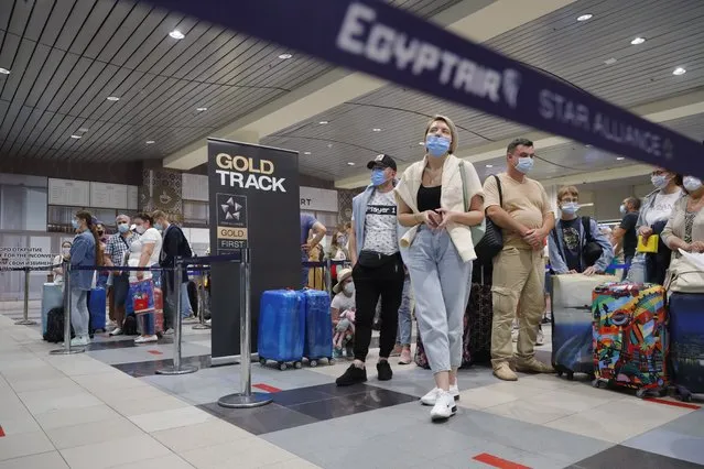 Russian tourists gather at the Egyptair check-in desk at the Domodedovo International Airport outside Moscow, Russia, Monday, August 9, 2021. The Russian state aviation agency, Rosaviatsiya, has cleared eight Russian airlines to operate flights to Hurghada and Sharm El Sheikh from 43 cities all across Russia. (Photo by Alexander Zemlianichenko Jr/AP Photo)