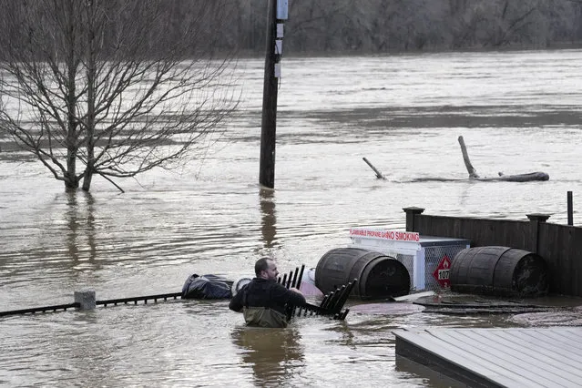 Nathan Sennett wades to retrieve furniture in hip-deep water on the patio of the Quarry Tap Room, Tuesday, December 19, 2023, in Hallowell, Maine. Waters continue to rise in the Kennebec River following Monday's severe storm. (Photo by Robert F. Bukaty/AP Photo)