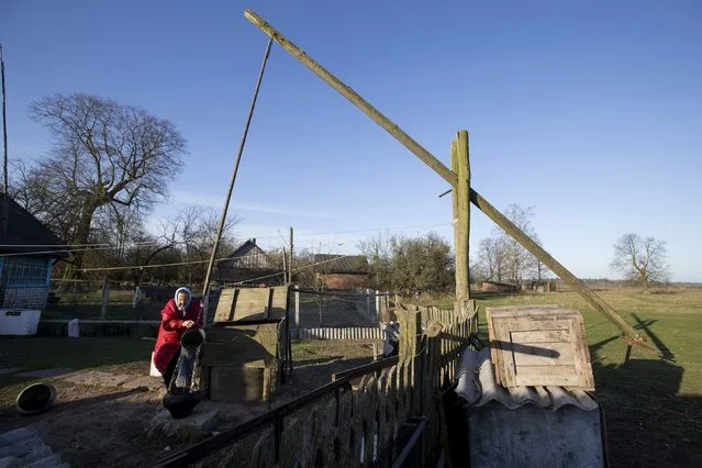 Nastia Pokolo, 74, takes water from an old well near her house in the village of Babinets, southwest of the capital Minsk, April 17, 2015. Pokolo, one of just three residents of the village situated in a remote region near the Belovezhskaya Pushcha National Park and about 10 km (6 miles) away from the border with Poland, lives alone separately from her daughter's and two sons' families. (Photo by Vasily Fedosenko/Reuters)