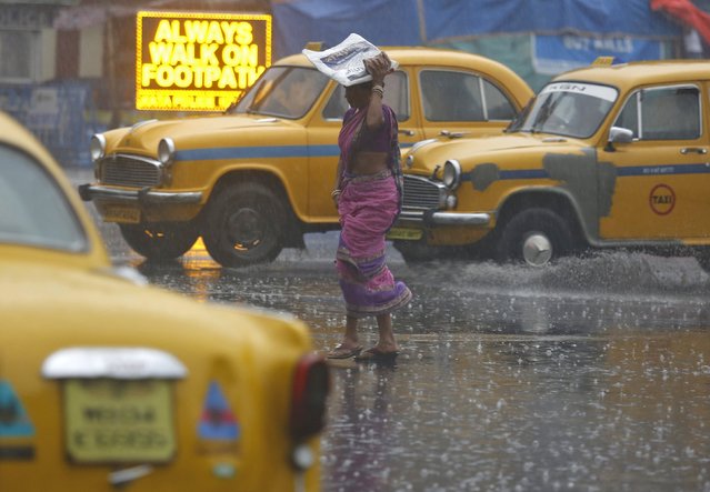 A woman cover her head with a plastic bag as she crosses a road during a heavy downpour in Kolkata, India, February 24, 2016. (Photo by Rupak De Chowdhuri/Reuters)