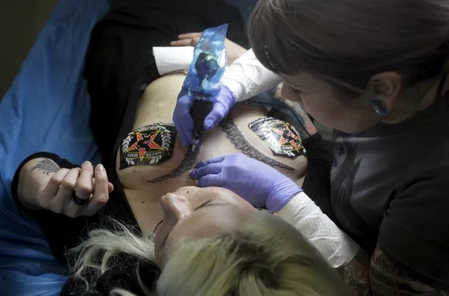 An artist draws a tattoo on a woman's chest during a tattoo convention in Ljubljana April 18, 2015. (Photo by Srdjan Zivulovic/Reuters)