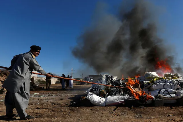 Pakistani customs employee torches a pile of confiscated contraband and narcotics during a campaign marking International Customs Day in Karachi, Pakistan January 26, 2017. (Photo by Akhtar Soomro/Reuters)