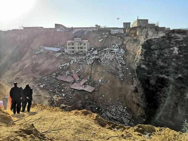 Rescue workers look at the site of a landslide that caused buildings to collapse in Xiangning county in northern China's Shanxi province Saturday, March 16, 2019. Hundreds of police, firefighters and medical personnel joined rescue efforts on Saturday after a landslide in northern China knocked down several buildings, killing some and leaving others missing. (Photo by Chinatopix via AP Photo)