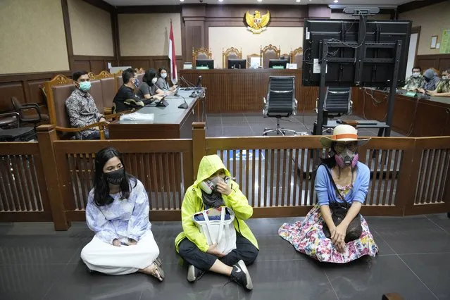 Activist wearing masks to represent those affected by air pollution, sit on the floor in protest before judges announce their verdict on a civil lawsuit filed against several Indonesian officials, including President Joko Widodo and Jakarta Governor Anies Baswedan for their failure to improve poor air quality in the capital city, inside a courtroom at Central Jakarta District Court in Jakarta, Indonesia, Thursday, September 16, 2021. The court ruled Thursday that President Widodo and six other top officials have neglected to fulfill citizens' rights to clean air and ordered them to improve the poor air quality in the capital. (Photo by Dita Alangkara/AP Photo)