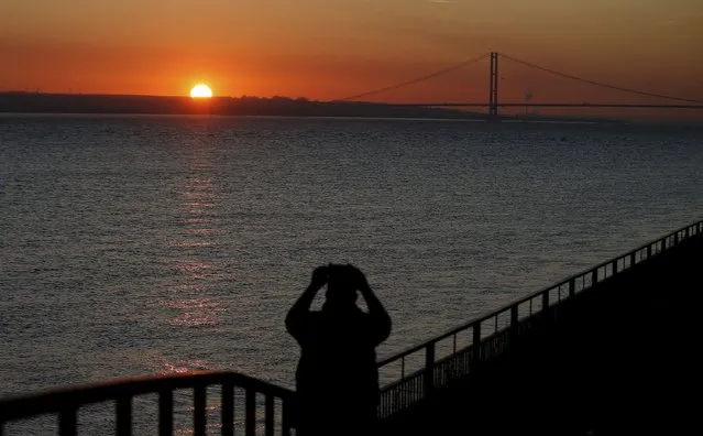A man takes a photograph of the sun setting behind the Humber Bridge in Hull, Britain, November 29, 2016. (Photo by Andrew Yates/Reuters)