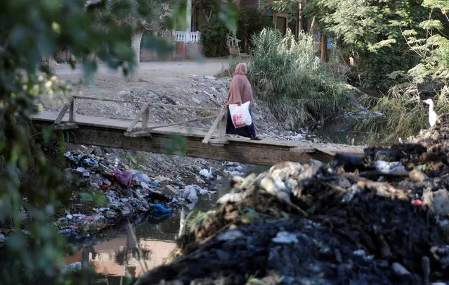 A woman crosses a bridge surrounded by litter and waste at a canal connected to the river Nile near the agricultural road which leads to the capital city of Cairo, Egypt December 5, 2016. (Photo by Amr Abdallah Dalsh/Reuters)