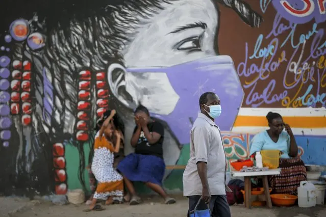 A man walks past an information mural telling people to wear masks to prevent the spread of the coronavirus, on a street in Mombasa, Kenya Monday, September 27, 2021. (Photo by Brian Inganga/AP Photo)