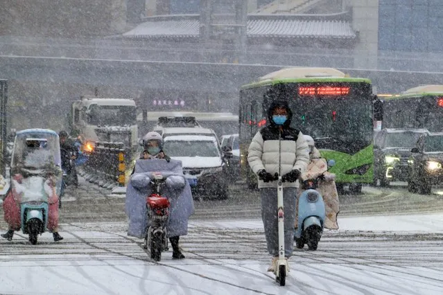 Motorists move through a street during a snowfall in Xi'an in northwest China's Shaanxi province, Wednesday, February 21, 2024. Heavy snow has blanketed northern and central China, disrupting traffic and forcing schools to cancel classes. (Photo by Chinatopix via AP Photo)