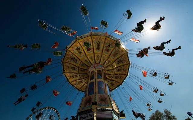 On the first day of the 81st Stuttgart Spring Festival in Baden-Wuerttemberg, Stuttgart on April 20, 2019, visitors drive a few laps in the chain carousel on the Cannstatter Wasen. (Photo by Christoph Schmidt/dpa)