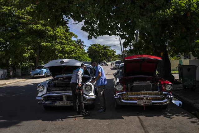 Drivers of two vintage American cars check their vehicles in Varadero, Cuba, Wednesday, September 29, 2021. (Photo by Ramon Espinosa/AP Photo)