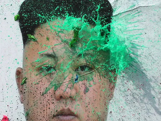 A balloon thrown by a North Korean defector containing a colored liquid bursts on a portrait of North Korean leader Kim Jong Un during a rally protesting North Korea Wednesday, March 30, 2016, in Seoul, South Korea. North Korea fired a short-range projectile from an area near its eastern coast on Tuesday, South Korean officials said, in what appears to be another weapons test seen as a response to ongoing military drills between Washington and Seoul. (Photo by Ahn Young-joon/AP Photo)