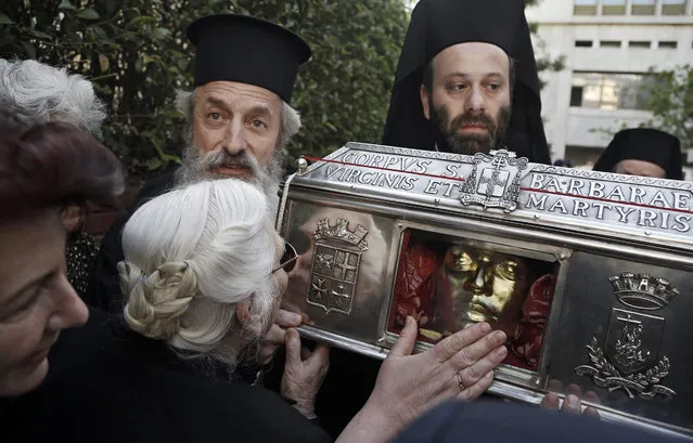 Greek Orthodox believers pay their respects to the holy relics of St. Barbara, which came from Venice, outside the St. Savvas state cancer hospital in Athens, Greece, 15 May 2015. Hundreds of pilgrims have being waiting outside the Saint Savvas state cancer hospital in Athens for the arrival of the relics of Saint Barbara (Agia Varvara in Greek) forcing the police to divert traffic around the hospital. (Photo by Yannis Kolesidis/EPA/)