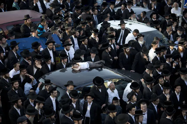 Ultra-Orthodox Jews watch the funeral procession of Rabbi of the Kaliv Hasidic dynasty and Holocaust survivor Menachem Mendel Taub during his funeral in Jerusalem, Sunday, April 28, 2019. Thousands attended the Jerusalem funeral of Menachem Mendel Taub, scion of a Hungarian rabbinic dynasty, who died Sunday aged 96. Taub helped produce a two-volume encyclopedia documenting Jewish religious martyrs killed in the Holocaust. His death comes days before Israel marks Holocaust Remembrance Day, honoring six million Jews killed by Nazi Germany. (Photo by Ariel Schalit/AP Photo)