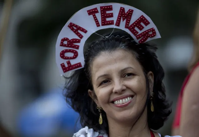 A reveler wears a crown that reads in Portuguese: “Out Temer” during a carnival street party in Rio de Janeiro, Brazil, Friday, February 24, 2017. (Photo by Silvia Izquierdo/AP Photo)