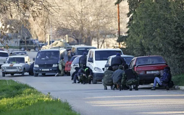 Members of pro-Russian self-defence units take cover behind cars outside a military base in the Crimean town of Belbek near Sevastopol March 22, 2014. (Photo by Vasily Fedosenko/Reuters)