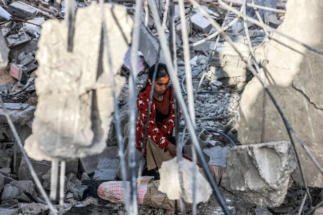 A girl salvages items from the rubble of a collapsed building in Rafah in the southern Gaza Strip on April 24, 2024 following reported Israeli air strikes overnight amid the ongoing conflict in the Palestinian territory between Israel and the militant group Hamas. (Photo by Mohammed Abed/AFP Photo)