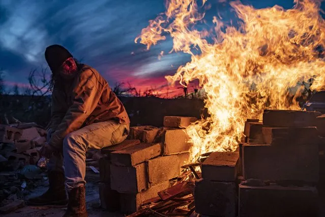 Thomas Shelby makes a fire as he prepares to stay the night by the rubble of his home to protect from potential looters in Dawson Springs, Kentucky, on Saturday, December 11, 2021. One or more tornados tore through Dawson Springs late last night. (Photo by Austin Anthony/The Washington Post)