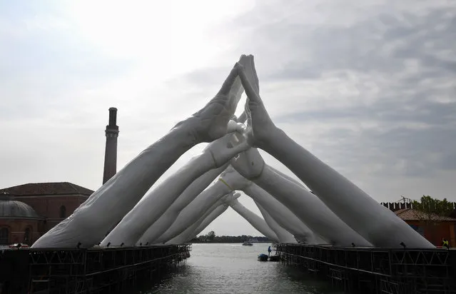 A general view shows Italian artist's Lorenzo Quinn's “Building Bridges”, a sculptural installation showing six pairs of arching hands creating a bridge over a Venetian waterway in the Arsenale former shipyard, ahead of the 58th Internatinal Venice Biennale art exhibition on May 8, 2019 in Venice. (Photo by Tiziana Fabi/AFP Photo)