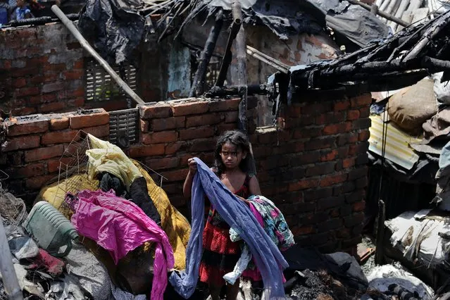 A fire victim Najia Khatoon tries to remove garments within her burned  home after a massive fire blaze destroyed 600 shanties in a slum at Park Circus in Calcutta, Eastern India on 06 April 2014. Huge number of shanties were gutted and destroyed in a midnight fire that broke out in a slum near Park Circus railway station. Fire officials said the flames were first noticed at midnight and within minutes nearly all the shanties were engulfed in fire. Noboby was injured. (Photo by Piyal Adhikary/EPA)