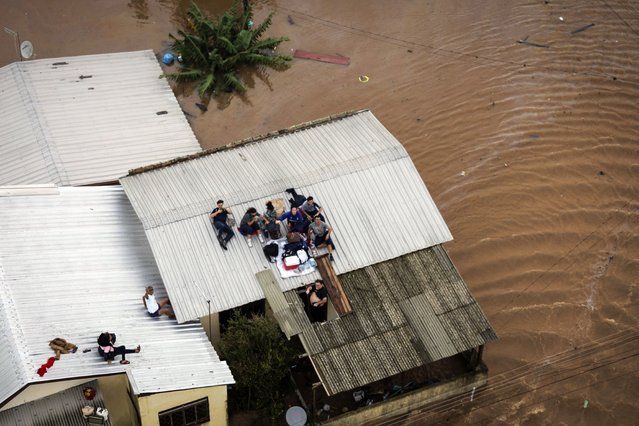 People wait to be rescued by a Brazilian Army helicopter during an operation in conjunction with firefighters to rescue people trapped in their homes due to a flood, in Canoas, Porto Alegre, Brazil, 04 May 2024. According to the latest report from the Government of Rio Grande do Sul, whose capital is Porto Alegre, the floods have caused the death of 57 people in the state, to which another victim is added in the neighboring state of Santa Catarina. Furthermore, in Rio Grande do Sul there are 67 missing people, as well as 32,640 people who have had to evacuate their homes to go live with relatives and friends, and another 9,581 who have moved to public shelters. (Photo by Isaac Fontana/EPA)