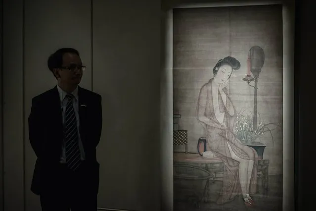 An employee of Sotheby's stands by an artwork titled “Meiren at Her Bath” during the preview of the exhibition “Gardens of Pleasure: s*x in Ancient China” in Hong Kong on April 15, 2014. Explicit works of Chinese erotic art went on display, as Dutch collector Ferdinand Bertholet aims to bring the lost art of eroticism back to the country. (Photo by Philippe Lopez/AFP Photo)