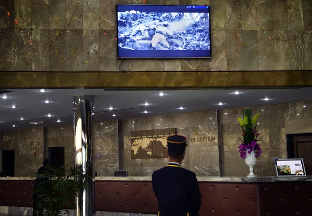 A bell man at the Yanggakdo Hotel where foreigners stay watches a film featuring American casualties and hitler from World War II in Pyongyang, North Korea on May 5, 2016. (Photo by Linda Davidson/The Washington Post)