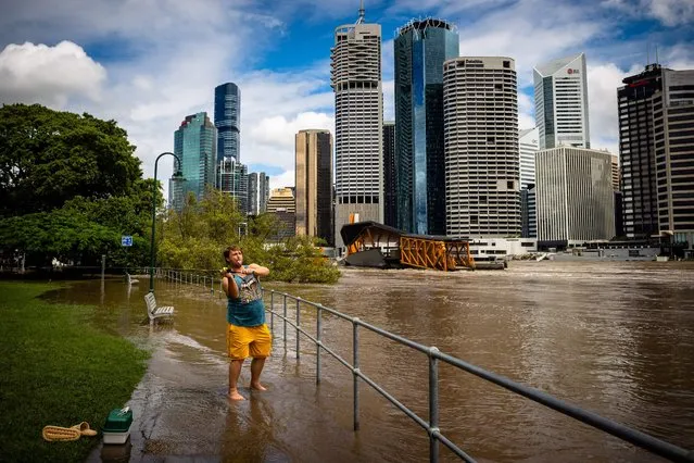 A man casts a fishing line into the swollen Brisbane River in Brisbane on February 28, 2022, following heavy rains and nearby flooding. (Photo by Patrick Hamilton/AFP Photo)