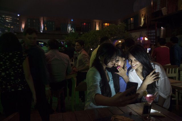 In this June 11, 2015 photo, Indian girls take a selfie at a party hosted by “TrulyMadly”, one of India's online dating apps in Gurgaon, India. Hundreds of thousands of young Indians are nervously exploring online dating apps, breaking with India's centuries-old traditions governing marriage and social conduct. (Photo by Tsering Topgyal/AP Photo)