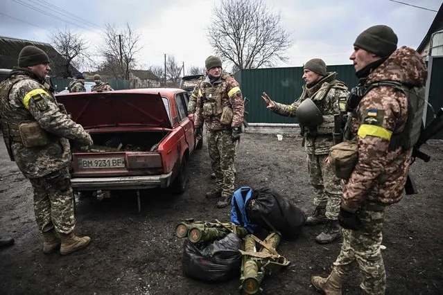 Ukrainian soldiers unload weapons from the trunk of an old car, northeast of Kyiv on March 3, 2022. A Ukrainian negotiator headed for ceasefire talks with Russia said on March 3, 2022, that his objective was securing humanitarian corridors, as Russian troops advance one week into their invasion of the Ukraine. (Photo by Aris Messinis/AFP Photo)