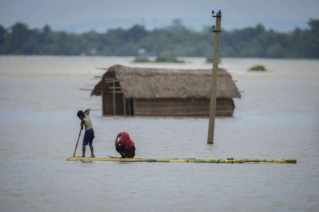 A young boy rows a makeshift banana raft to cross the flood water in Morigaon district in the northeastern Indian state of Assam, India, Wednesday, July 3, 2024. (Photo by Anupam Nath/AP Photo)