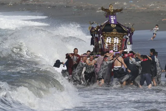 Participants carry a portable shrine, or mikoshi, into the sea during a purification rite at the annual Hamaori Festival in Chigasaki, west of Tokyo early Monday, July 20, 2015. (Photo by Koji Sasahara/AP Photo)