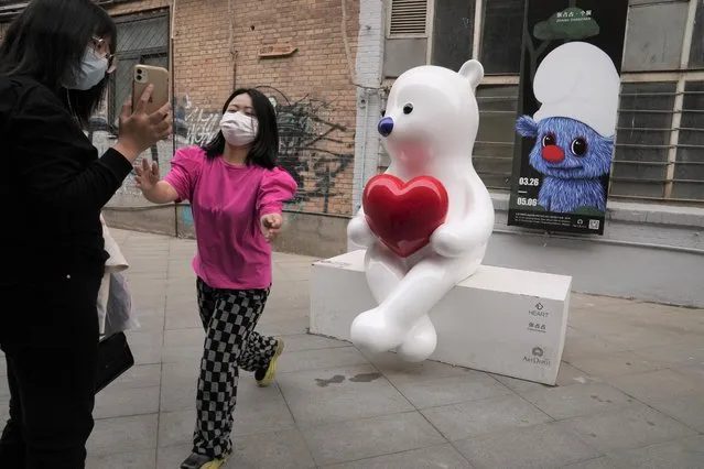 Visitors wearing masks take photos with art works at the 798 art district where access is controlled due to pandemic measures on Sunday, April 10, 2022, in Beijing. (Photo by Ng Han Guan/AP Photo)