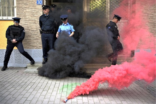 Police officers walk away from flares thrown by protesters during a demonstration on May Day (Labour Day), to mark the international day of the workers, in Pristina, Kosovo on May 1, 2023. (Photo by Armend Nimani/AFP Photo)