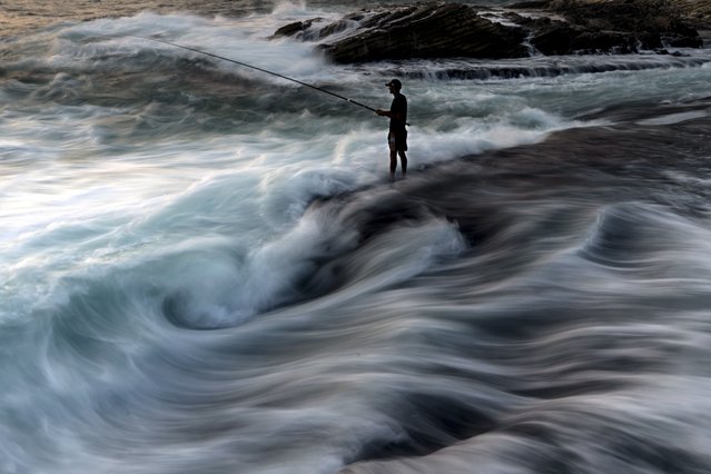 A fisherman casts his fishing line into the Mediterranean Sea from a rocky area along the Beirut coastline, on a sweltering hot day, in Beirut, Lebanon, Saturday, July 27, 2024. (Photo by Hassan Ammar/AP Photo)