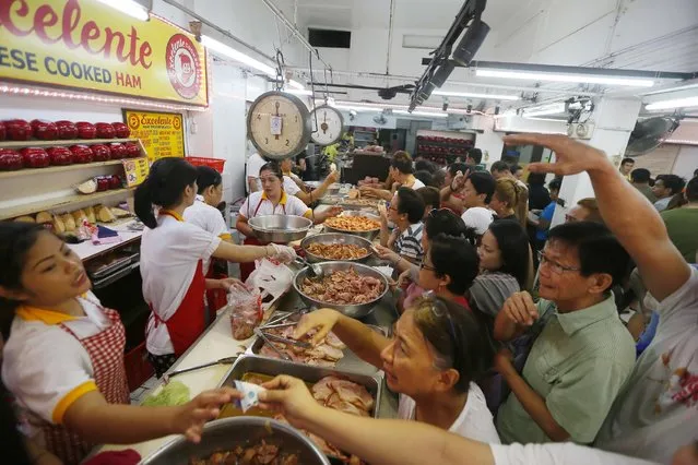 People buy Chinese ham as part of the preparations to welcome the new year, Saturday, December 31, 2016, in Manila, Philippines. Filipinos usually put at least twelve different round fruits that have the circular shape of coin money on their dinning table to symbolize prosperity for the coming New Year. (Photo by Bullit Marquez/AP Photo)