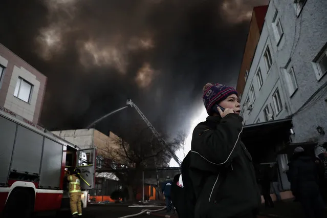 A boy walks on a street as Russian fire fighters extinguish a burning warehouse in the southern outskirt of Moscow, Russia, 13 December 2019. The flames in the meantime have spread over some 7,000 square meters of the textile warehouse, authorities said, while two helicopters are helping to fight the blaze. There were no immediate reports of any casualties, but one fire fighter was injured and 25 ambulance cars and a special air testing vehicle are at the site, media reported. (Photo by Maxim Shipenkov/EPA/EFE)