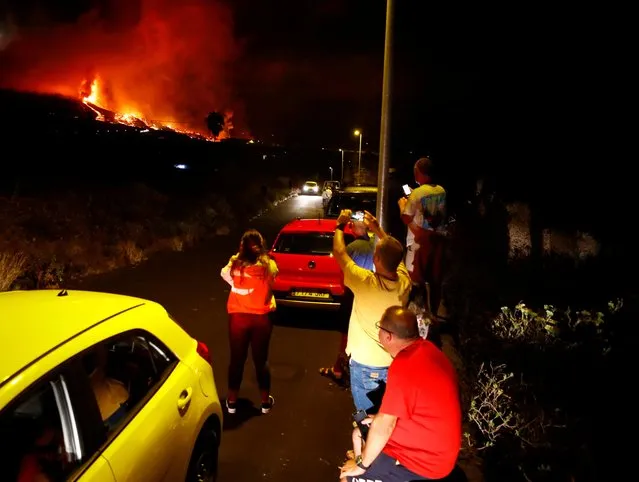 Residents watch lava following the eruption of a volcano in the Cumbre Vieja national park at El Paso, on the Canary Island of La Palma, September 19, 2021. (Photo by Borja Suarez/Reuters)