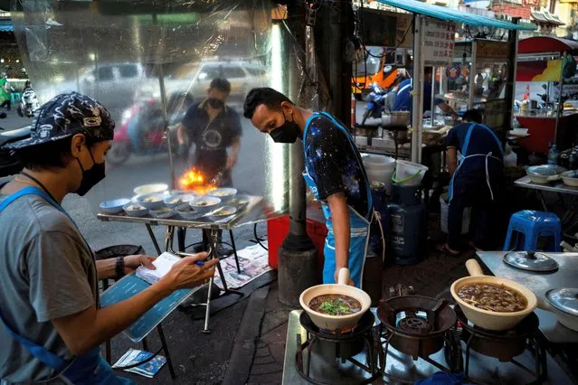 People wearing face masks as protection against the coronavirus disease (COVID-19) sell street food in Bangkok's Chinatown, Thailand, March 17, 2022. (Photo by Athit Perawongmetha/Reuters)