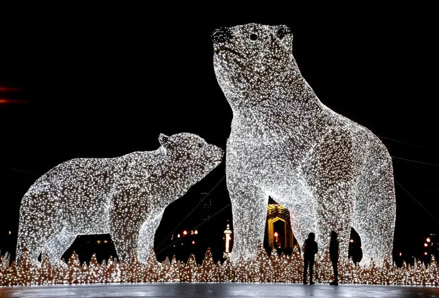 People walk along a seasonally decorated street with huge light sculptures of polar bears installed at the Gorky Park in Moscow, Russia, 17 December 2019. Russians are preparing to celebrate New Year's Eve on 31 December and Christmas which is observed on 07 January, according to the Russian Orthodox Julian calendar 13 days after Christmas on 25 December on the Gregorian calender. (Photo by Maxim Shipenkov/EPA/EFE)