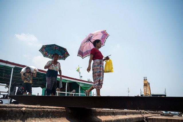 Women walk under umbrellas to shelter from the sun on a hot day in Yangon on April 25, 2024. Extreme heat is scorching parts of South and Southeast Asia, prompting health warnings from authorities as high temperatures are recorded across the region. (Photo by Sai Aung Main/AFP Photo)