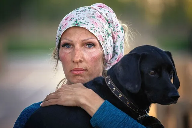 A woman holds her dog after arriving from Russian-occupied territory at a registration and processing area for internally displaced people in Zaporizhzhia, in Ukraine, on May 8, 2022. (Photo by Dimitar Dilkoff/AFP Photo)