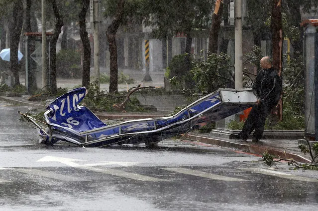 A man drags a sign brought down by strong winds from Typhoon Soudelor in Taipei, Taiwan, Saturday, August 8, 2015. (Photo by Wally Santana/AP Photo)
