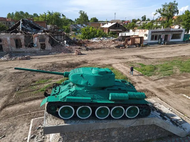 A young woman walks next to a damaged Soviet tank monument on June 2, 2022 in Trostyanets, Ukraine. Russian forces occupied large swaths of the Sumy region after Moscow invaded Ukraine on Feb. 24, before Ukrainian forces retook control of the area in April. Russia has since concentrated its war effort in the south and east of the country. (Photo by Alexey Furman/Getty Images)