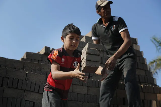 Alejandro, 9, catches bricks to pass over to a man who puts them in the kiln at a brick factory run by his uncles in Tobati, Paraguay, Monday, August 31, 2020. Members of brickmaking families said school closures due to COVID-19, scheduled to last at least until December, have led to many children and adolescents working longer hours, making it difficult to complete their virtual schoolwork. (Photo by Jorge Saenz/AP Photo)