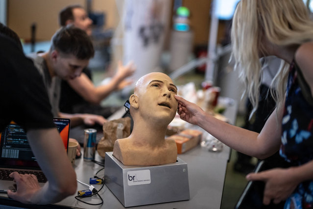 A visitor touches the head of a humanoid robot at the booth of Hanson Robotics company during the world's largest gathering of humanoid AI Robots as part of International Telecommunication Union (ITU) AI for Good Global Summit in Geneva, on July 5, 2023. The United Nations is convening this week a global gathering to try to map out the frontiers of artificial intelligence and to harness its potential for empowering humanity, hoping to lay out a clear blueprint on the way forward for handling AI, as development of the technology races ahead the capacity to set its boundaries. (Photo by Fabrice Coffrini/AFP Photo)