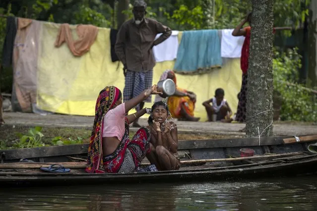 A flood affected woman bathes her daughter near Tarabari village, west of Gauhati, in the northeastern Indian state of Assam, Monday, June 20, 2022. (Photo by Anupam Nath/AP Photo)