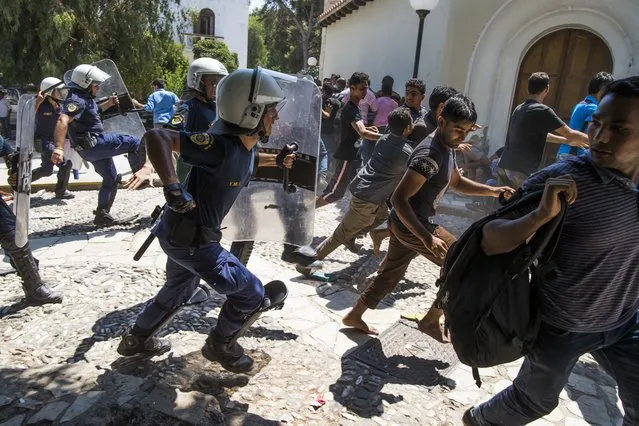 Greek riot police officers chase away migrants as they started shouting  while waiting to be registered near a police station Monday August 17, 2015 on the Greek island of Kos  after crossing from Turkey. Authorities on Kos were overwhelmed by the influx, and many locals vented anger at the crowds of refugees sleeping rough in parks and public spaces at the height of the key tourist season. (Photo by Alexander Zemlianichenko/AP Photo)